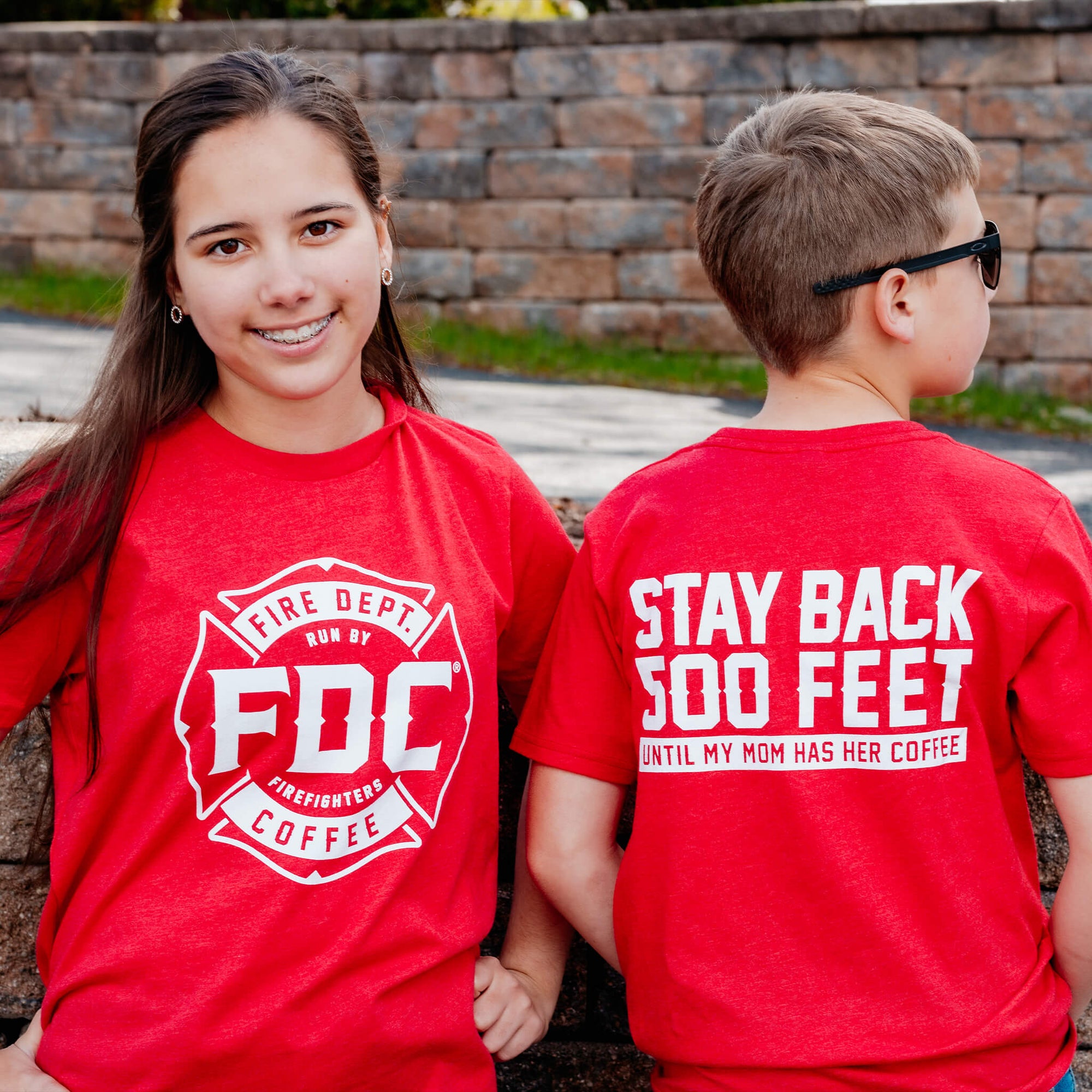 A youth-size red shirt that has the FDC maltese cross on the front and a back that reads, "Stay back 500 feet until my mom has her coffee"