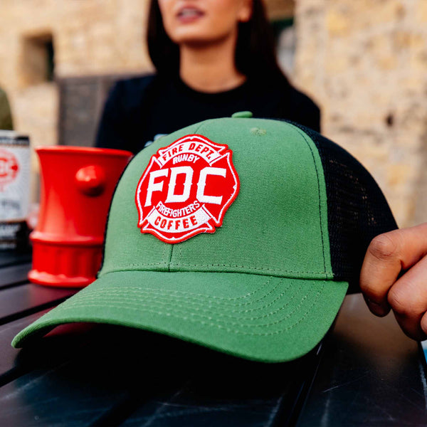 A 3/4 angle image of the FDC Green Hat featuring a green camo design with a red FDC Maltese cross logo on the front.