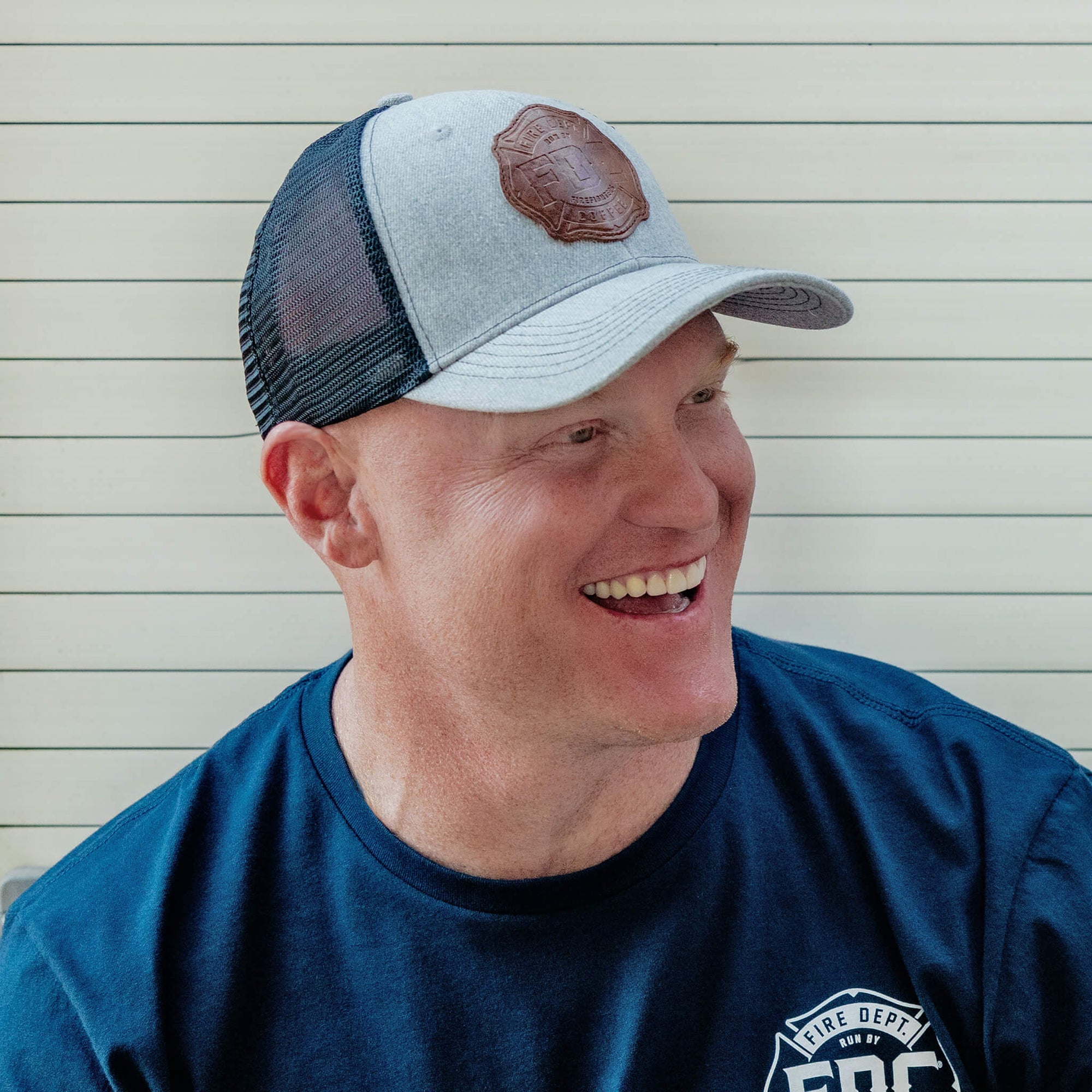 Front/side angle view of grey hat with black mesh back and a leather patch on the front of the FDC maltese cross logo