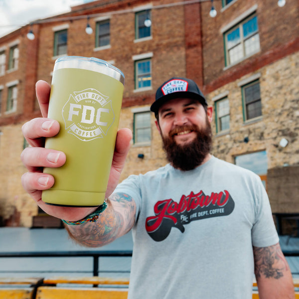 A 20 ounce green tumbler that has an FDC maltese cross logo engraved on the front