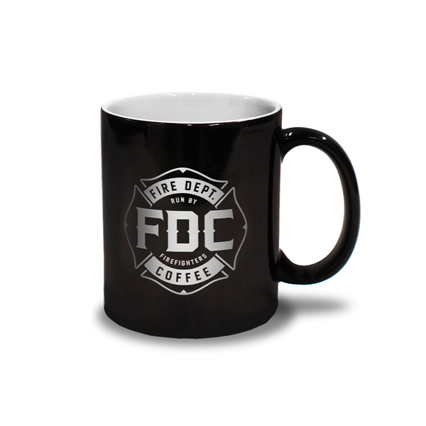 Two mugs: one showing the black mug with the FDC maltese cross logo on it when cold on the left, and the flames that appear on the mug when hot on the right.