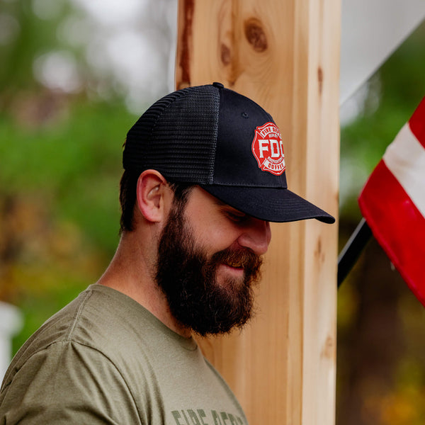 Side view of the front of the FDC black mesh hat with the FDC maltese cross logo on the front