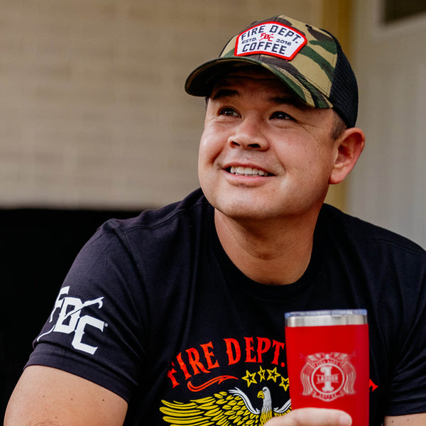 Camouflage hat with black mesh back and a Fire Department Coffee keystone patch on the front