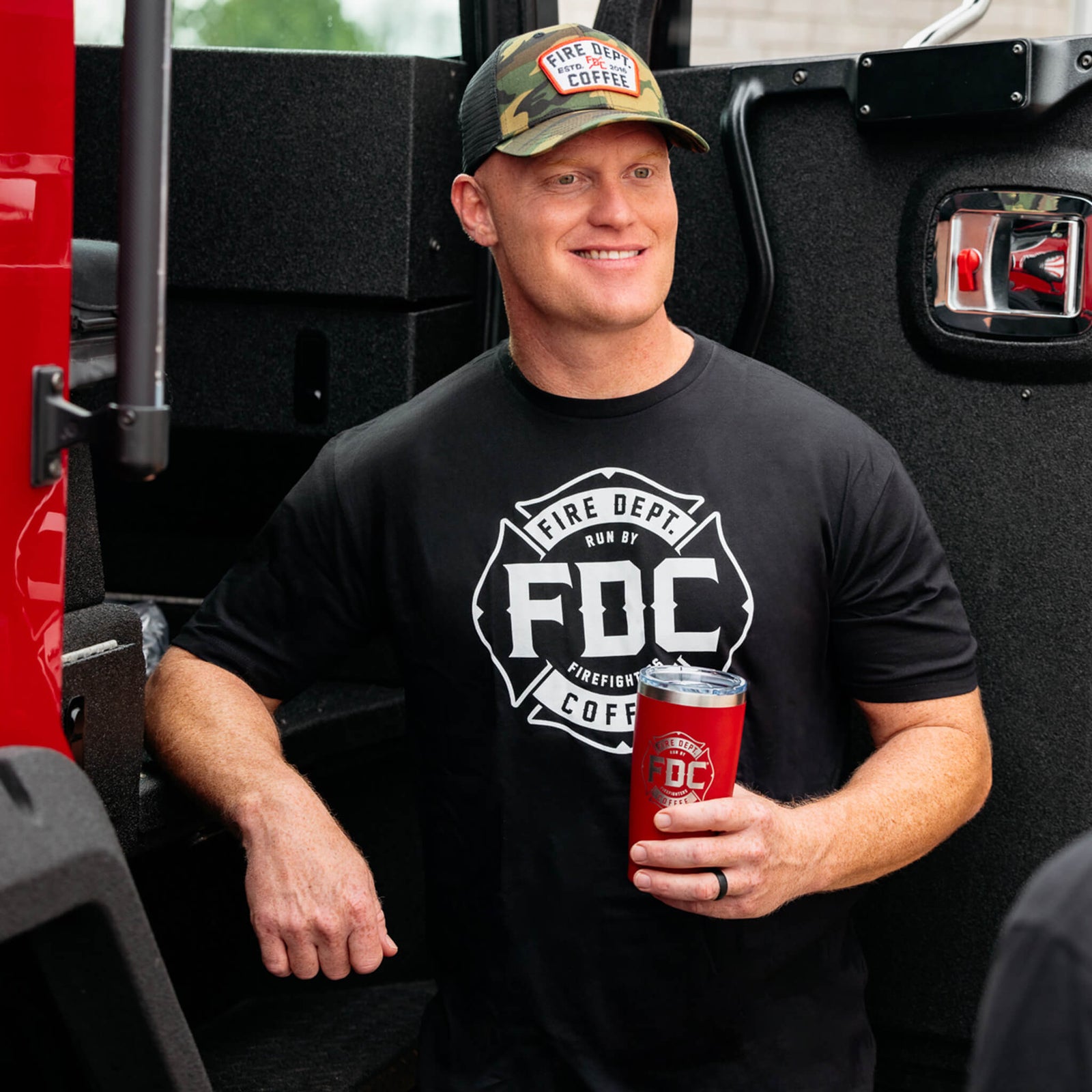 A black Fire Department Coffee T Shirt, featuring FDC's maltese cross logo in white.