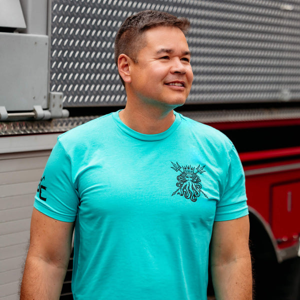 The back of teal Fire Department Coffee Shellback t shirt featuring a blue octopus with a humanoid face wearing a crown and holding two tridents.